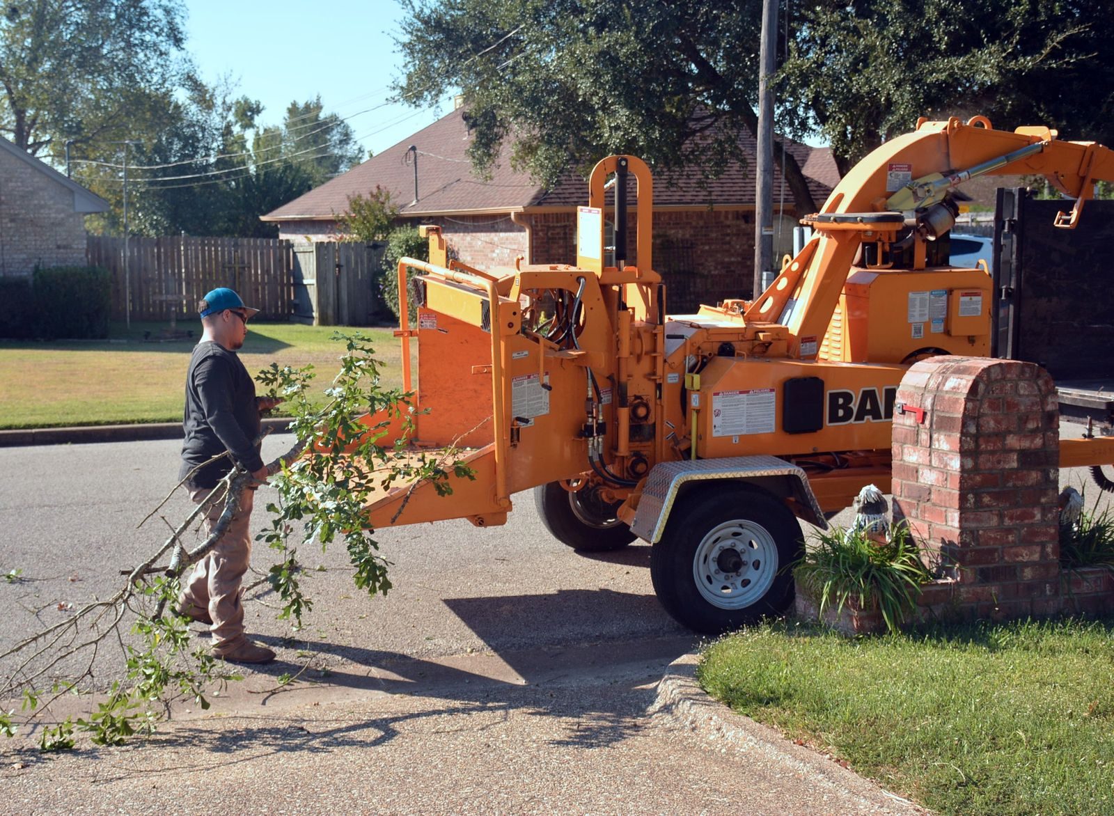Crew member feeding tree branches into a wood chipper on a residential street